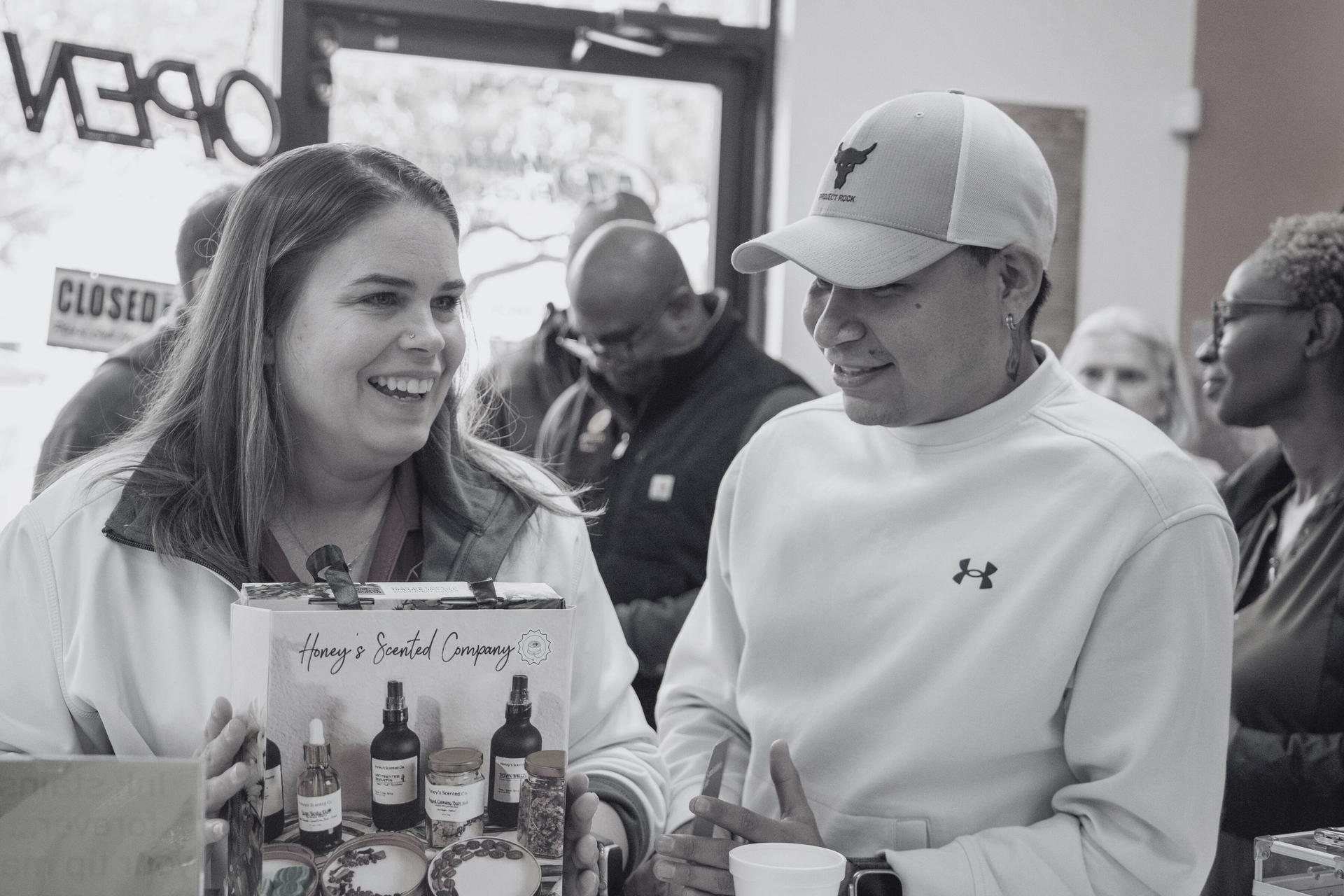 A North Texas business owner in conversation outside her shop, talking with a partner about her local product line.